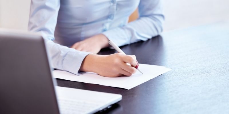 une personne entrain d'écrire un document à la main